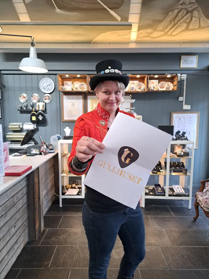 Gullhuset Odda May Helen viser frem logoen